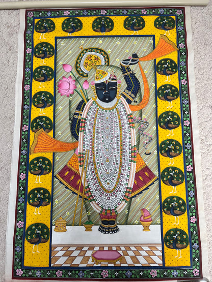 Close-up of Pichwai artwork showing intricate peacock border and fine brushwork